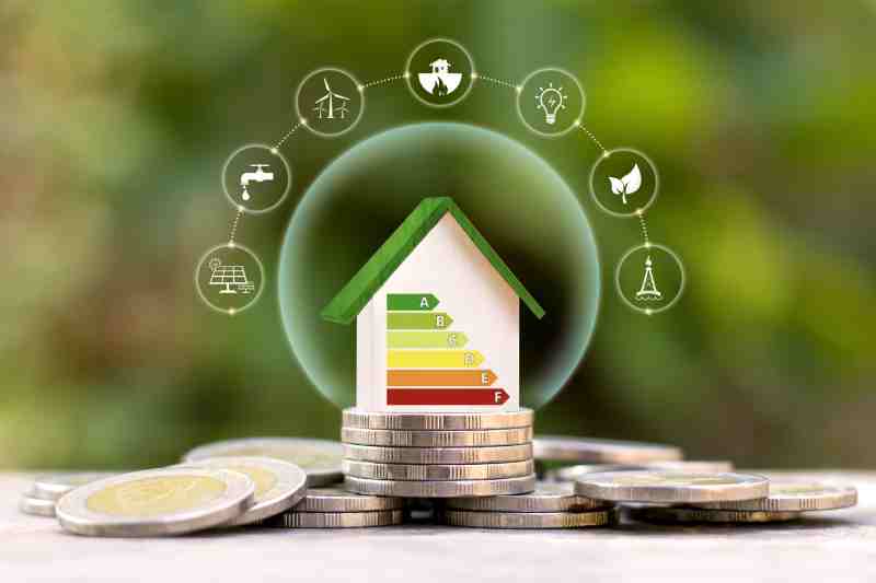 Energy-efficient house on coins with solar, wind, and water icons, representing clean air goals under the Clean Air Act.