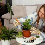 Woman tending a potted plant indoors, symbolizing comfort and a smaller ecological footprint.