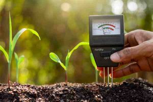 Person testing soil with a meter, symbolizing smart thermostat automation for reduced HVAC energy use.